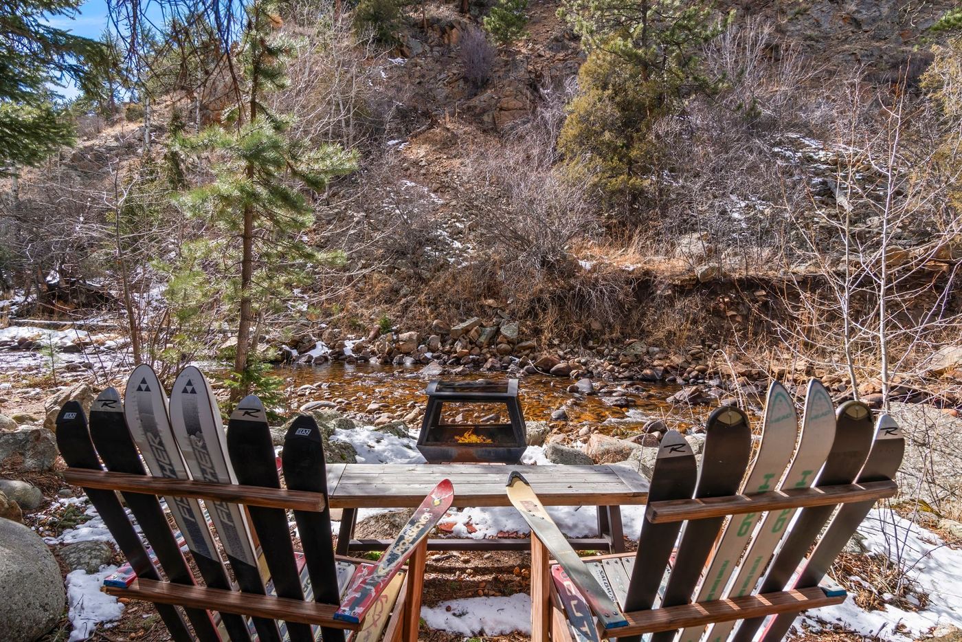 A fire pit and ski-slat chairs on the private beach at the water's edge in autumn
