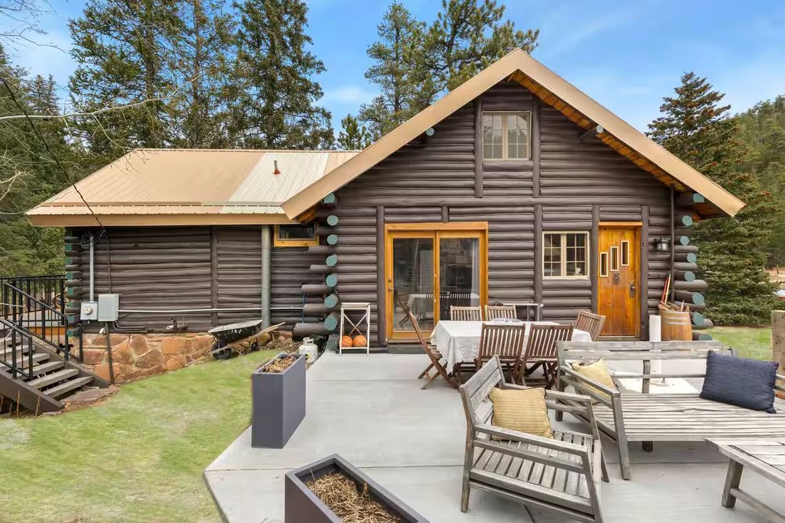 The Schaeffer log cabin with a stacked-stone chimney and flagstone patio