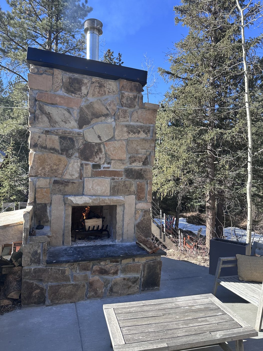 The stone outdoor fireplace lit on the terrace